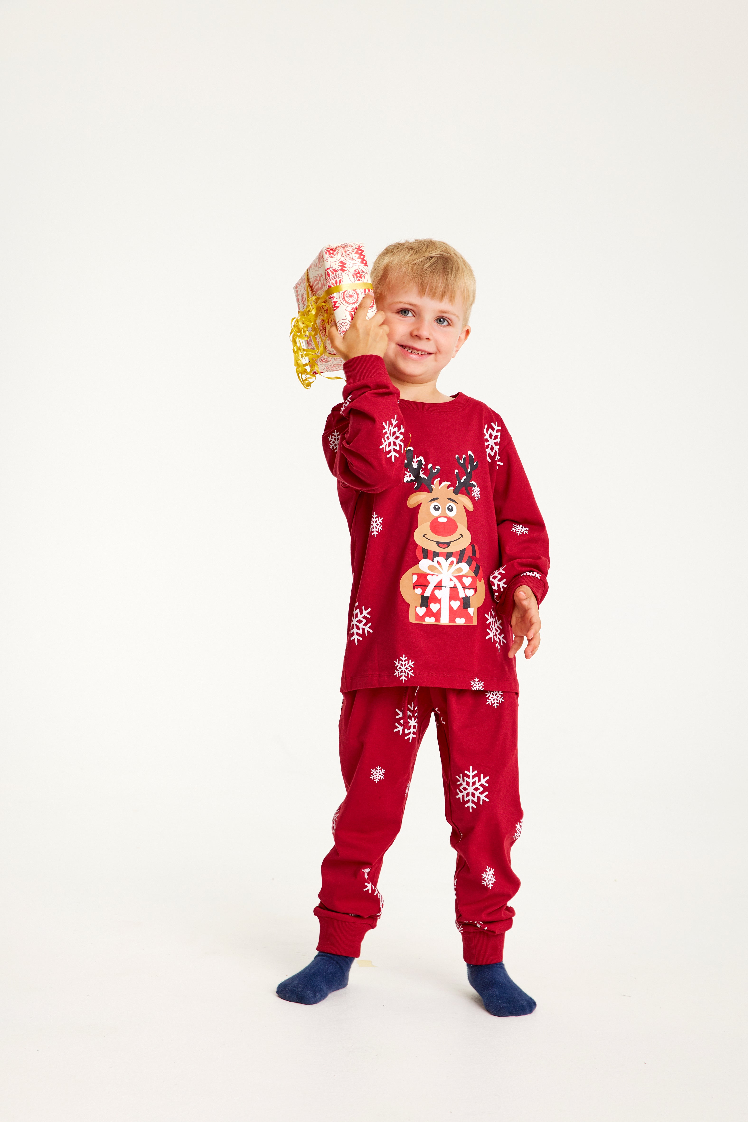 Ein Kind, das in einem roten Weihnachtspyjama mit Rudolph posiert.